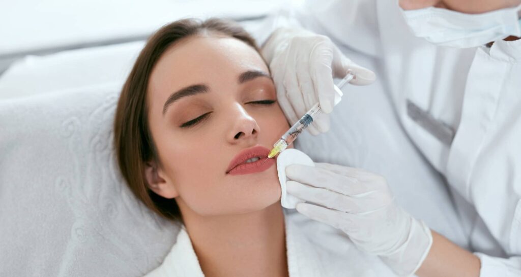 Femme recevant une injection d’acide hyaluronique dans les lèvres par un professionnel esthétique.